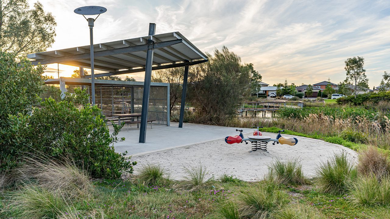 Svg+xml;charset=utf — tract Childrens round see saw in a sand pit next to a sheltered seating area